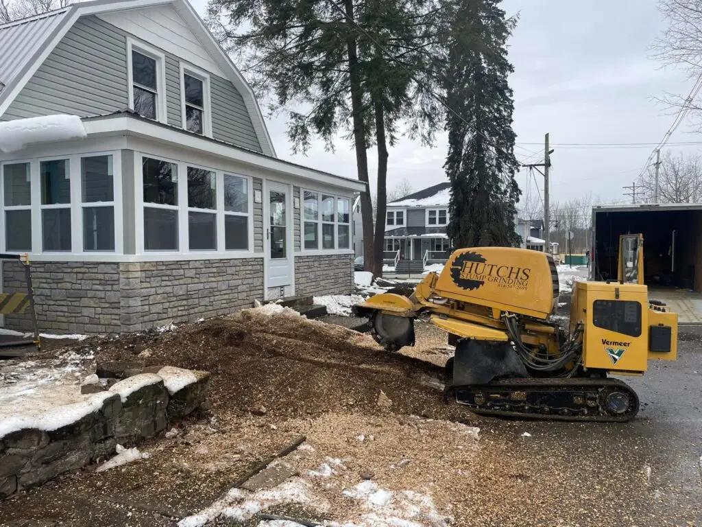 Stump grinding in front of a house